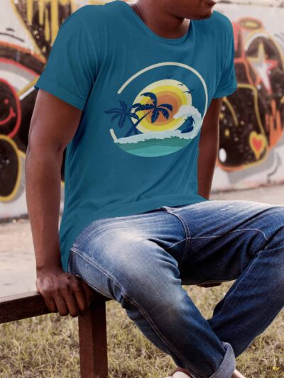 Person wearing a teal T-shirt with a tropical sunset and palm tree graphic, sitting on a railing in front of graffiti-art background.