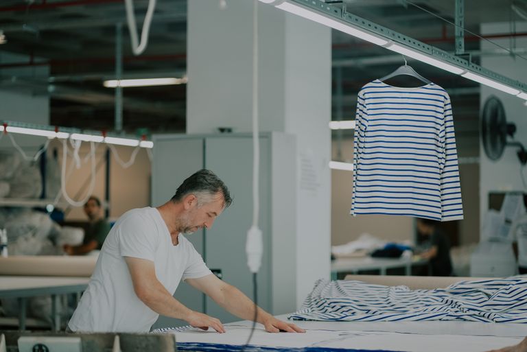 Adult male in a textile workshop working with striped fabric.