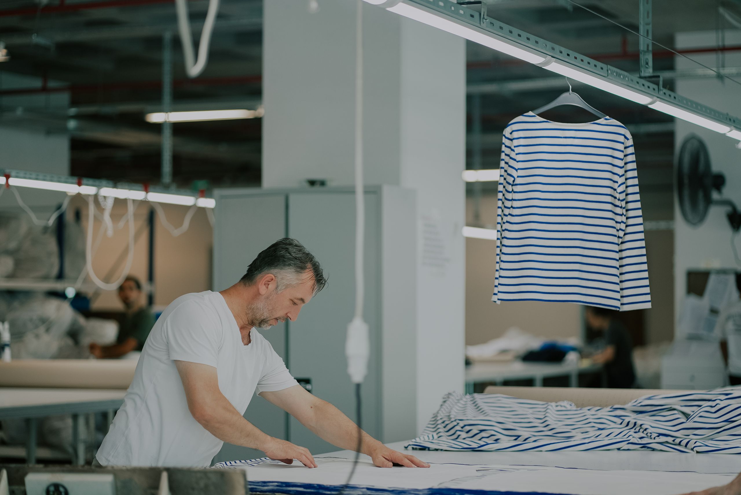 Adult male in a textile workshop working with striped fabric.