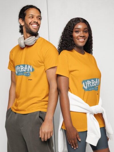 Two people stand back-to-back in orange T-shirts, smiling; the man has gray headphones around his neck and the woman has a white jacket tied around her waist.