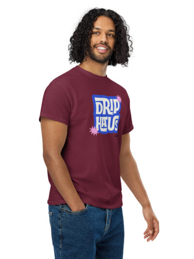 Portrait of a man with long curly hair wearing a maroon graphic t-shirt, facing slightly right and smiling.